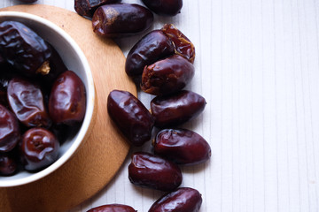 Dried dates fruit in ceramic bowl on wooden table. Top view.