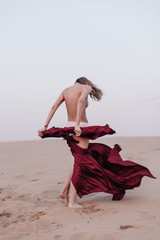 A girl with a fabric is standing in the wind in the desert