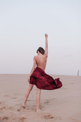 A girl with a fabric is standing in the wind in the desert