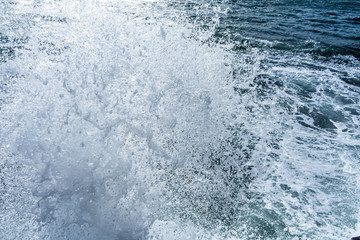 Water splashing. Crystal clear sea water beating against the rocks and cliffs. Sea waves break on the shore after a storm. Blue sky, sunny summer day, refreshing mediterranean sea water