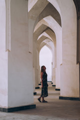 Fototapeta na wymiar Middle Asia. Uzbekistan Bukhara. white arched openings create a corridor. A girl is standing among them. Girl and buildings.