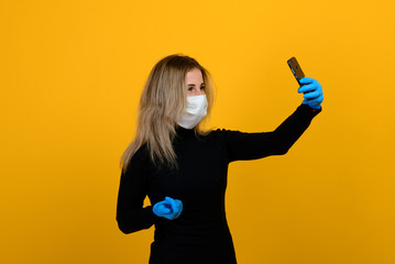 Portrait of a girl in a medical mask, which puts on a rubber glove. Yellow and grey background. Copy space.