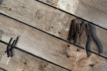 Pliers and bent nails old lie on a tree desktop. rust. cracked, scratched homemade table. construction background