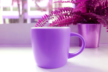 Pop art style vivid purple colored coffee mug with potted ferns on a table