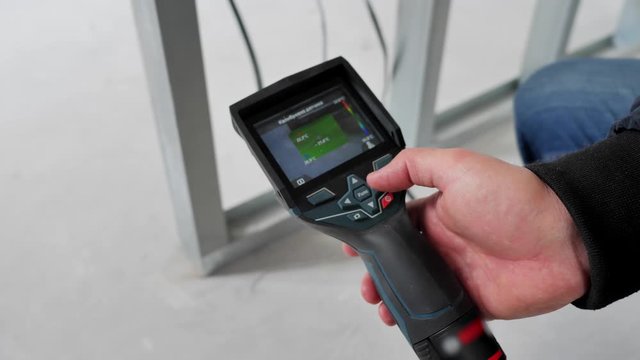 Close up. An engineer checks the heated floors with a thermal imager.