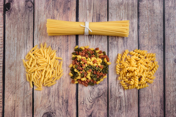 Different raw uncooked Italian pasta on wooden table against dark background. Diet and food concept. Top view. Lay flat.