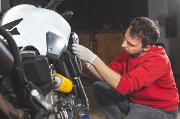 Man repairing, doing maintenance of his motorcycle, motorbike in the garage, reapir concept