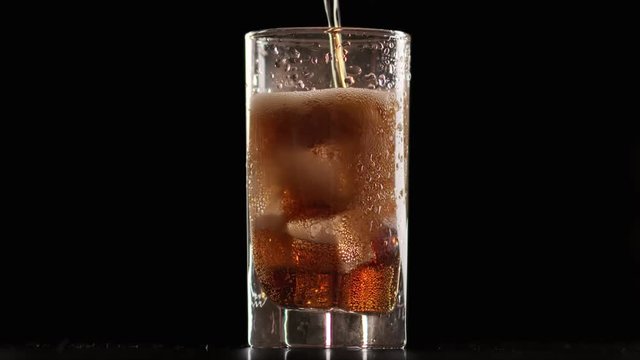 Stream of cold refresh drink fill in glass with iced cube slow motion. Shot with RED camera in 4K