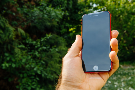 Paris, France - Apr 24, 2020: Holding in hand new iPhone SE by Apple Computers with plastic cover film touch ID, Single-lens rear camera and iPhone 8 design with internals from 11 Pro version