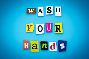 A word writing text - wash your hands. Cut letters on a blue background. Headline, banner with inscription. Coronavirus prevention concept.