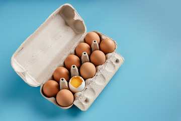 Chicken eggs in paper container box. Blue  isolated. Close up. Broken egg.