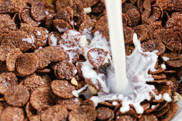 Bowl of chocolate flakes with milk splash. Top view.