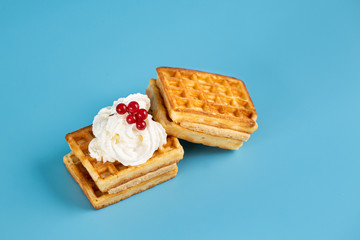 Waffles on an isolated blue background. Cream with berries on a waffle.