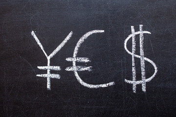 Fototapeta na wymiar Yen, Euro and Dollar signs written on a chalkboard