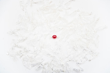 Wrapped red candy surrounded by empty candy wrappers. View from above. Isolated