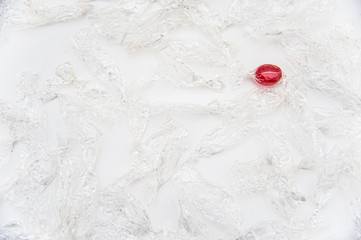 Transparent candy wrappers from candies and a red candy in the upper right corner. View from above. Isolated