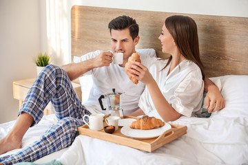 Morning of young couple having breakfast in bed