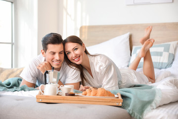Morning of young couple having breakfast in bed