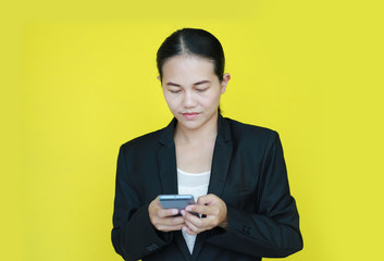 Portrait business woman working on smartphone in her hands isolated on yellow background.