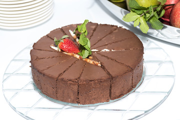 Whole round sliced dark chocolate cake with strawberry on top