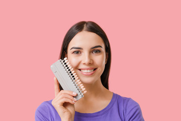 Fototapeta premium Beautiful young woman with teeth color samples on color background