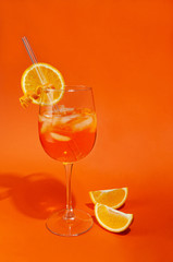 Aperol Spritz Cocktail. In a glass goblet with ice. And a glass tube for drinking. On a glass of orange slice. Near the glass there is a slice of orange. 