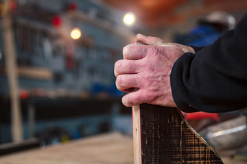 Male carpenter working on old wood in a retro vintage workshop.