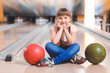 Fototapeta premium Little girl playing bowling in club