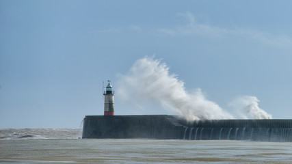 Massive waves crash over harbour wall onto lighthouse during huge storm on English coastline in...
