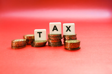 STacks of coins with tax lettering on top isolated on a red background,  Business and tax management concept