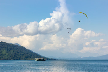 Parachute Flying over Water surface With Background Mountains Trees And Mist On a clear day in Laos. at Nam Ngum Dam Laos