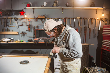 Male carpenter working on old wood in a retro vintage workshop.