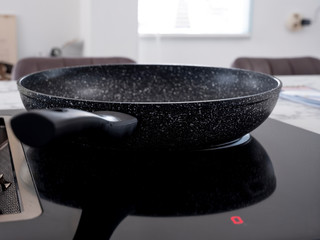frying pan on an induction plate in which pork chops are baking