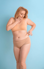 Troubled overweight woman on color background