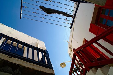 Greece, Mykonos island, white washed cubic traditional houses with color wooden balconies in the...