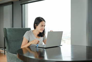 Portrait asian woman using laptop computer working on the table at home. People during the...