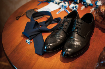 Black shoes blue cufflinks and blue tie on the table