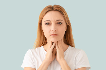 Woman with thyroid gland problem on light background