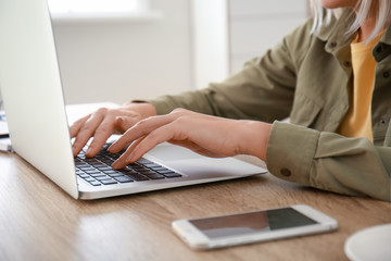 Mature woman using laptop for online learning at home, closeup