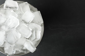 Metal bucket with ice cubes on black background, top view. Space for text