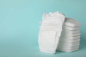 Stack of diapers on light blue background. Space for text