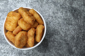 Bucket with tasty chicken nuggets on grey table, top view. Space for text