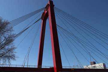 Steel bridge in red color called Willemsbrug in the center of Rotterdam over the Nieuwe Maas river in the Netherlands