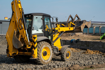 Yellow wheel loader Excavator machine working at construction site with a sand and gravel. Preparing of the fundament for a asphalting. Road construction site. Building of a parking.