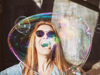 Beautiful girl in sunglasses and a big soap bubble near her face