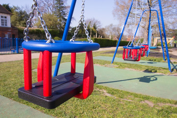Empty swings in children's playground in England during lockdown due to coronavirus quarantine for the prevention of COVID-19.