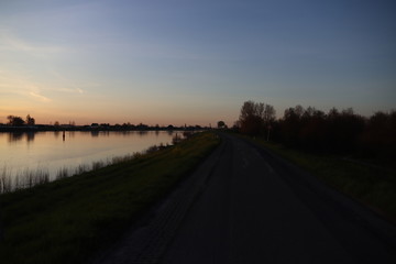 The sun rises over the water of the river Hollandsche IJssel near the dike at Park Hitland