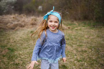 Adorable little girl playing in blooming apple tree garden on Easter egg hunt, runing and smiling....
