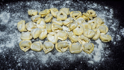 Delicious tortellini a ring-shaped pasta from Italy. Traditionally they are stuffed with a mix of meat, parmigiano reggiano cheese, egg and nutmeg. Black background