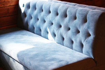 Blue sofa, textile. Upholstered furniture in the interior, a comfortable stylish sofa is standing by the window. Cafes and restaurants. Furniture and interior. Close-up